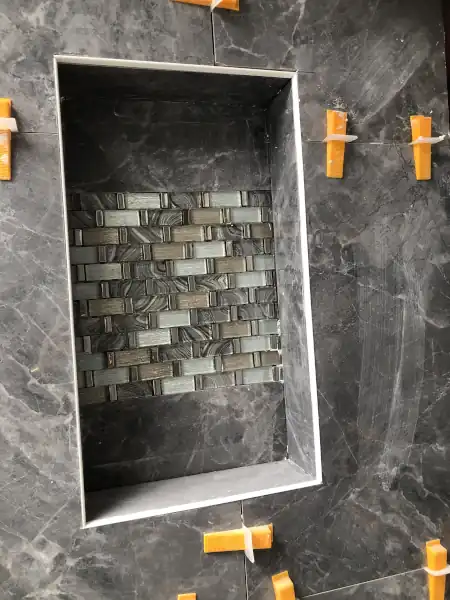 Marble tile shower niche with mosaic accent, installation in progress
