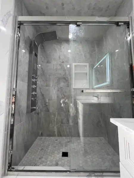 Finished glass-enclosed shower with grey marble tile surround, tiled by Munir Pro Tiles